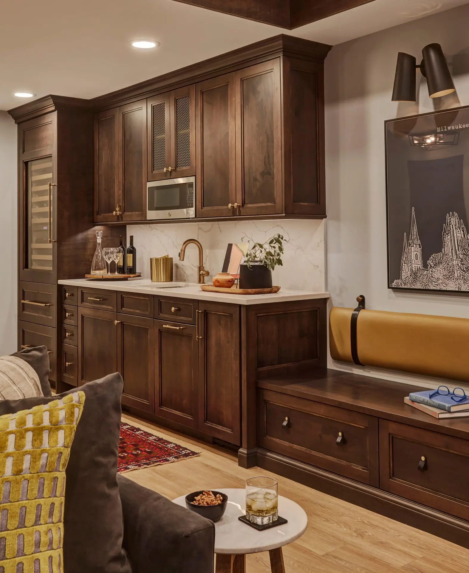 Dark wood built-in cabinetry with a microwave, sink, beverage refrigerator, and seating bench in a cozy room