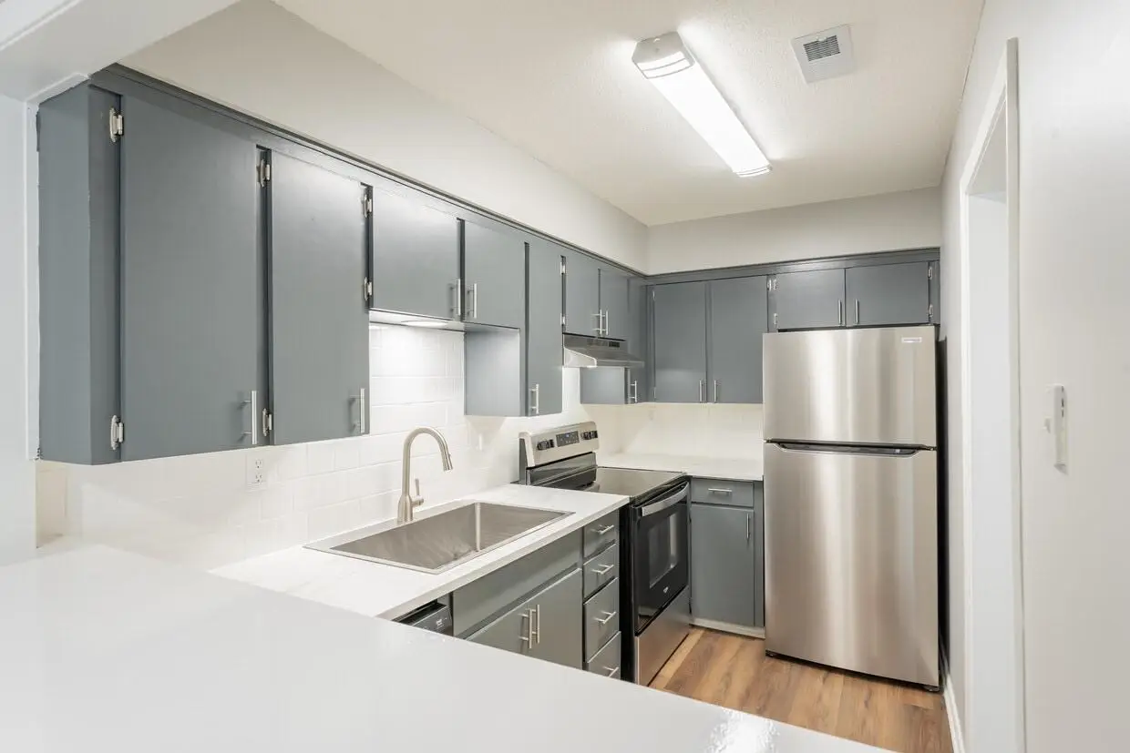 Bright kitchen with gray cabinets, white countertops, stainless steel appliances, and a double-basin sink