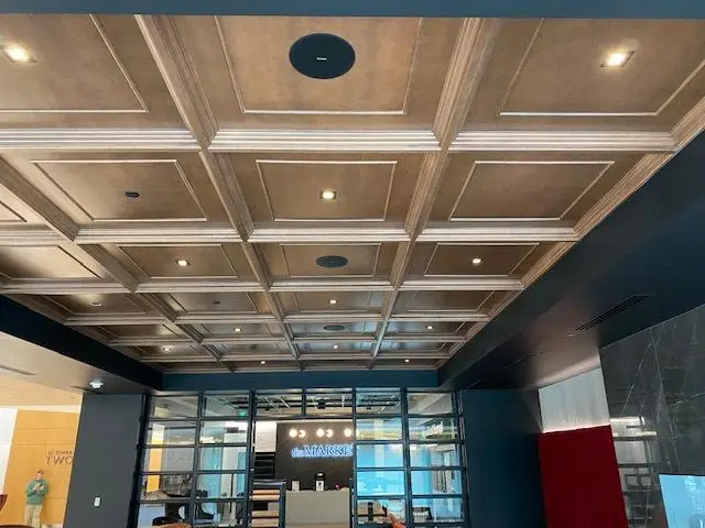 Modern lobby with a large decorative coffered ceiling, recessed lights, and glass entrance doors.