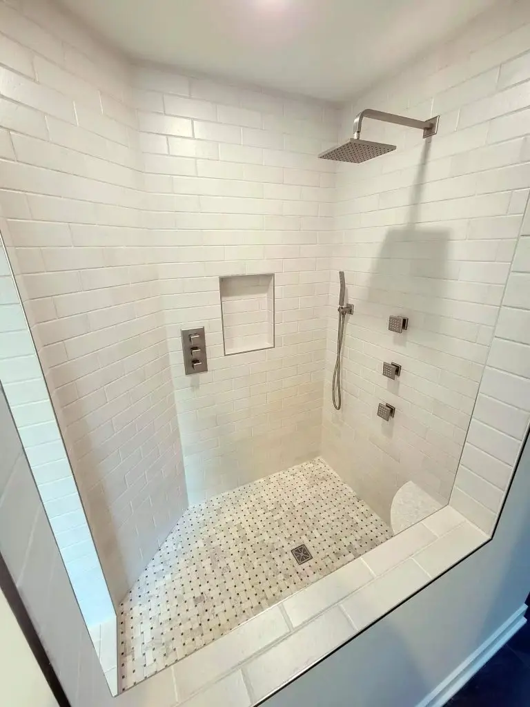Walk-in shower with white subway-tiled walls, a square rainfall showerhead, handheld shower wand, and small mosaic tile floor
